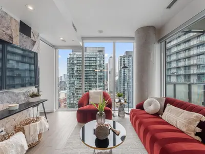 a living room with a red couch and large windows at The Aventi Suites - Downtown Toronto - Across TIFF Bell Lightbox in Toronto