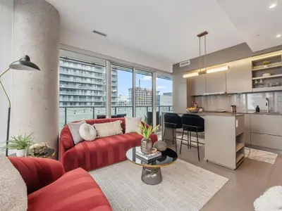 a living room with a red couch and a kitchen at The Aventi Suites - Downtown Toronto - Across TIFF Bell Lightbox in Toronto
