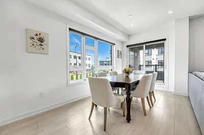 a dining room with a table and chairs and windows at Ritzy 3BR Home with Balcony Near Burlington Pier in Burlington