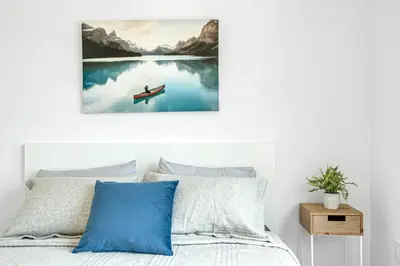 a bed with a painting of a boat on the water at Ritzy 3BR Home with Balcony Near Burlington Pier in Burlington