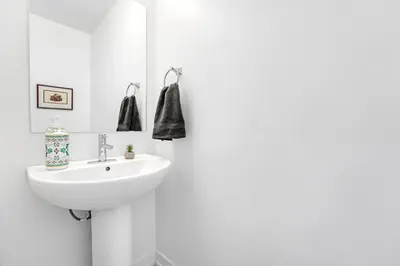 a white bathroom with a sink and a mirror at Ritzy 3BR Home with Balcony Near Burlington Pier in Burlington