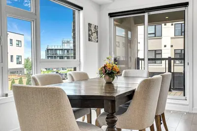 a dining room with a table and chairs and windows at Ritzy 3BR Home with Balcony Near Burlington Pier in Burlington