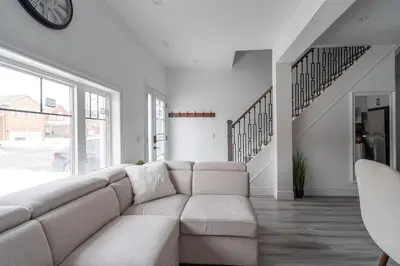 a white living room with a couch and stairs at Luxury 2 Bedroom 3 Bed Family Friendly Oasis with Smart Technology in Brampton