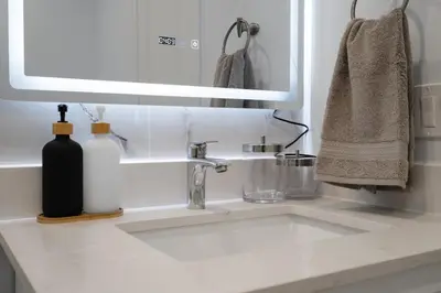 a white bathroom sink with a mirror and a sink at Luxury 2 Bedroom 3 Bed Family Friendly Oasis with Smart Technology in Brampton