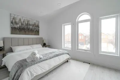 a white bedroom with a bed with two towels on it at Luxury 2 Bedroom 3 Bed Family Friendly Oasis with Smart Technology in Brampton