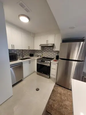 a kitchen with white cabinets and a stainless steel refrigerator at Cozy 2 Bed Rooms Apartment in Prime Location! in Mississauga