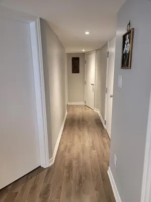 an empty hallway with white walls and wood floors at Cozy 2 Bed Rooms Apartment in Prime Location! in Mississauga
