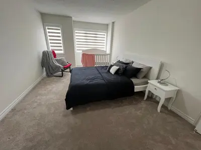 a bedroom with a bed and a chair and windows at Entire 4BR Detached Home 15 Mins from the Falls, in Thorold, Perfect for 10 guests in Thorold