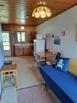 a living room with a blue couch and a kitchen at Wymbolwood Lodge in Tiny