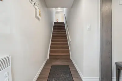 a staircase in a house with white walls and wooden floors at Wintergreen Spacious 2 Story Townhome Sauna 2 Min Walk to Village in Blue Mountains