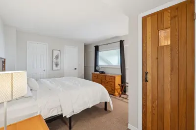 a bedroom with a white bed and a wooden door at Wintergreen Spacious 2 Story Townhome Sauna 2 Min Walk to Village in Blue Mountains