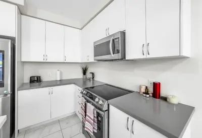 a kitchen with white cabinets and a microwave at Modern Comfort in Clarington in Newcastle