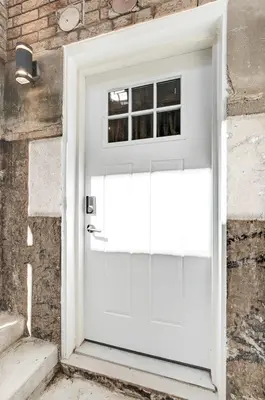 a white door with a window on a brick wall at Luxury & private 3 bed basement unit kitchen, wifi, park, mall in London
