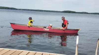 three people in a red boat on the water at The Mayflower - 4 Pine Forest in Cherry Valley
