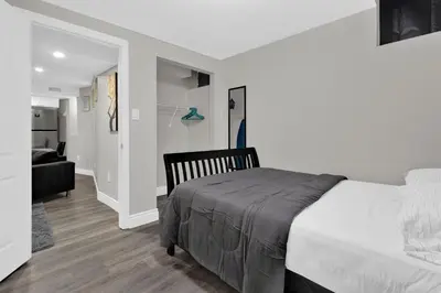 a white bedroom with a bed and a living room at Cozy Ancaster Hamilton Apartment in Hamilton