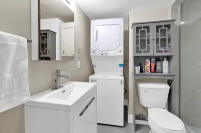 a white bathroom with a toilet and a sink at Cozy Ancaster Hamilton Apartment in Hamilton