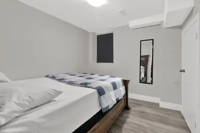 a white bedroom with a bed and a mirror at Cozy Ancaster Hamilton Apartment in Hamilton