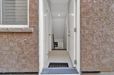 a hallway with a brick wall and a welcome mat at Cozy Ancaster Hamilton Apartment in Hamilton