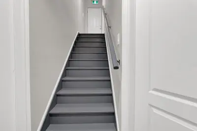 a stairway leading up to a room with white walls at Cozy Ancaster Hamilton Apartment in Hamilton