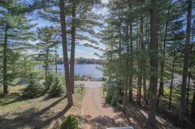 a path through the trees next to a lake at Villa Marina Haven private Waterfront in Port Carling