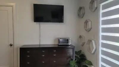 a room with a dresser with a television on a wall at Comfortable Getaway in Hamilton