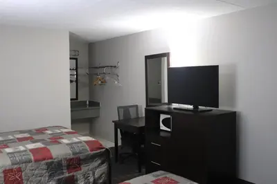 a bedroom with a bed and a desk with a television at Fort York Motel in Mississauga