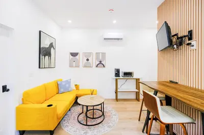 a living room with a yellow couch and a table at Adorable Modern Master Bedroom near Colleges and K-town in Toronto