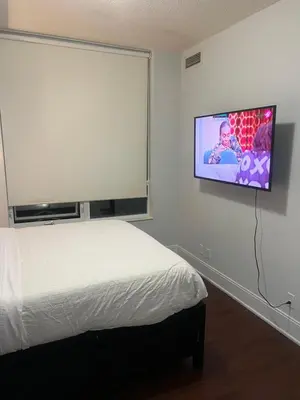 a bedroom with a bed and a flat screen tv on the wall at Cozy Ensuite private room homestay in Mississauga