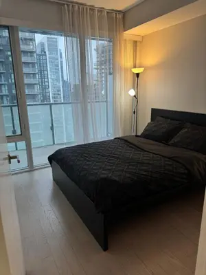 a bedroom with a bed and a large window at Cozy 1 Bedroom Downtown in Toronto