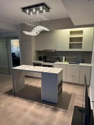 a kitchen with white cabinets and a large white island at Cozy 1 Bedroom Downtown in Toronto