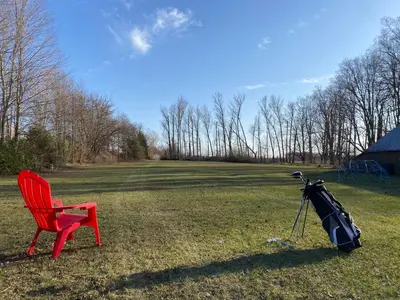 a red chair and a tripod in a field at Spacious Beach Town Retreat - Sleeps 8 in Port Elgin