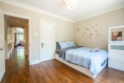 a white bedroom with a bed and a hardwood floor at 3 Bedroom Luxury House in Toronto in Toronto