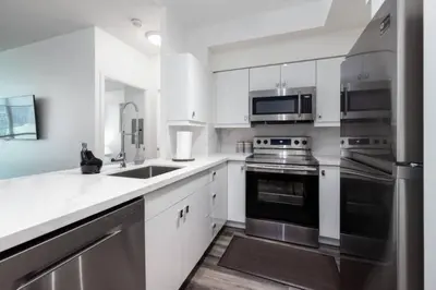 a kitchen with white cabinets and stainless steel appliances at Chic 1BR Condo Lake and City Views plus Free Parking in Toronto
