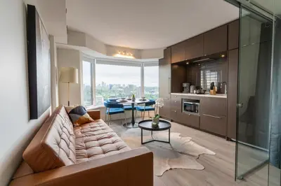 a living room with a couch and a table at Chic 1BR plus Den Condo Near ROM and CN Tower in Toronto