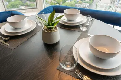 a table with plates and cups and a plant on it at Chic 1BR plus Den Condo Near ROM and CN Tower in Toronto