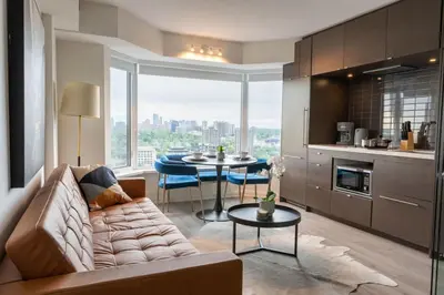 a living room with a couch and a table at Chic 1BR plus Den Condo Near ROM and CN Tower in Toronto