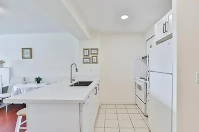 a white kitchen with a sink and a refrigerator at Cozy 1BR Condo with Balcony and Parking in Toronto