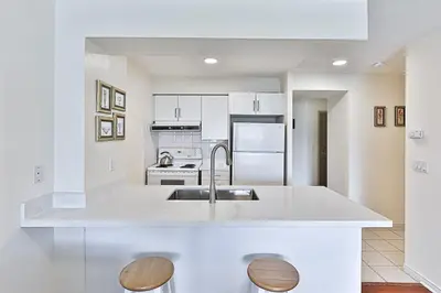 a white kitchen with a sink and a stove at Cozy 1BR Condo with Balcony and Parking in Toronto