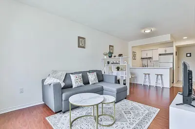 a living room with a couch and a kitchen at Cozy 1BR Condo with Balcony and Parking in Toronto