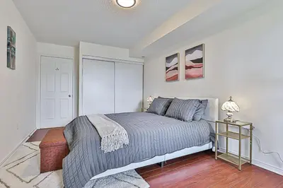 a bedroom with a bed and a table with a lamp at Cozy 1BR Condo with Balcony and Parking in Toronto
