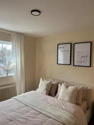 a bedroom with a bed with white sheets and a window at Cozy Bohemian Apartment in Toronto