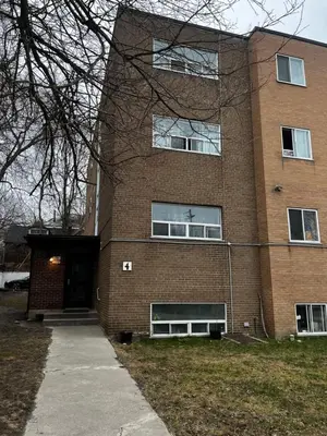 a large brick building with a door and a sidewalk at Cozy Bohemian Apartment in Toronto