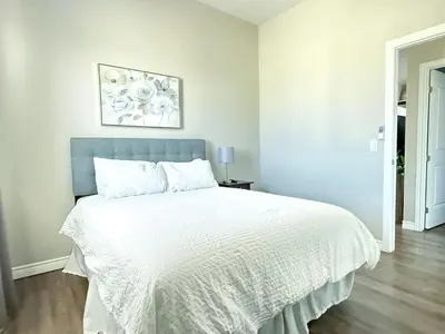 a white bed with a blue headboard in a bedroom at Contemporary East Loft in Historic Niagara in Niagara on the Lake