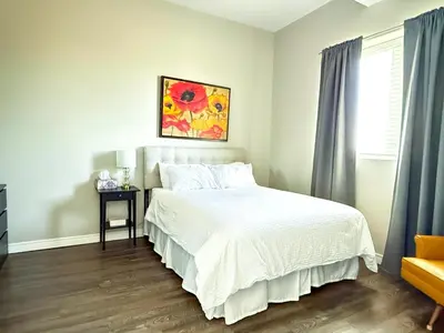 a bedroom with a bed and a painting on the wall at Contemporary East Loft in Historic Niagara in Niagara on the Lake
