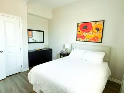 a bedroom with a white bed and a painting on the wall at Contemporary East Loft in Historic Niagara in Niagara on the Lake