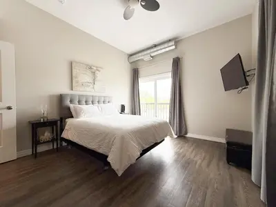 a white bedroom with a bed and a window at Contemporary West Loft in Historic Niagara in Niagara on the Lake
