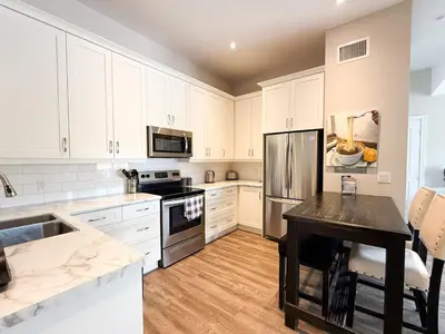 a kitchen with white cabinets and stainless steel appliances at Contemporary West Loft in Historic Niagara in Niagara on the Lake