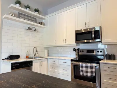 a kitchen with white cabinets and a stove top oven at Contemporary West Loft in Historic Niagara in Niagara on the Lake