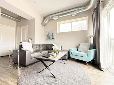 a living room with a gray couch and a blue chair at Contemporary West Loft in Historic Niagara in Niagara on the Lake