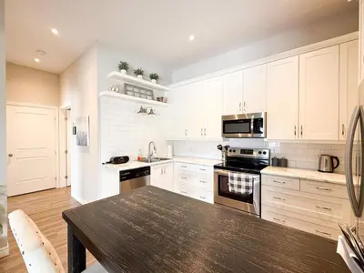 a kitchen with white cabinets and a wooden table at Contemporary West Loft in Historic Niagara in Niagara on the Lake